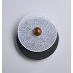 Lunara Textured Disc Wall Sconce in Black Travertine and Frosted Glass